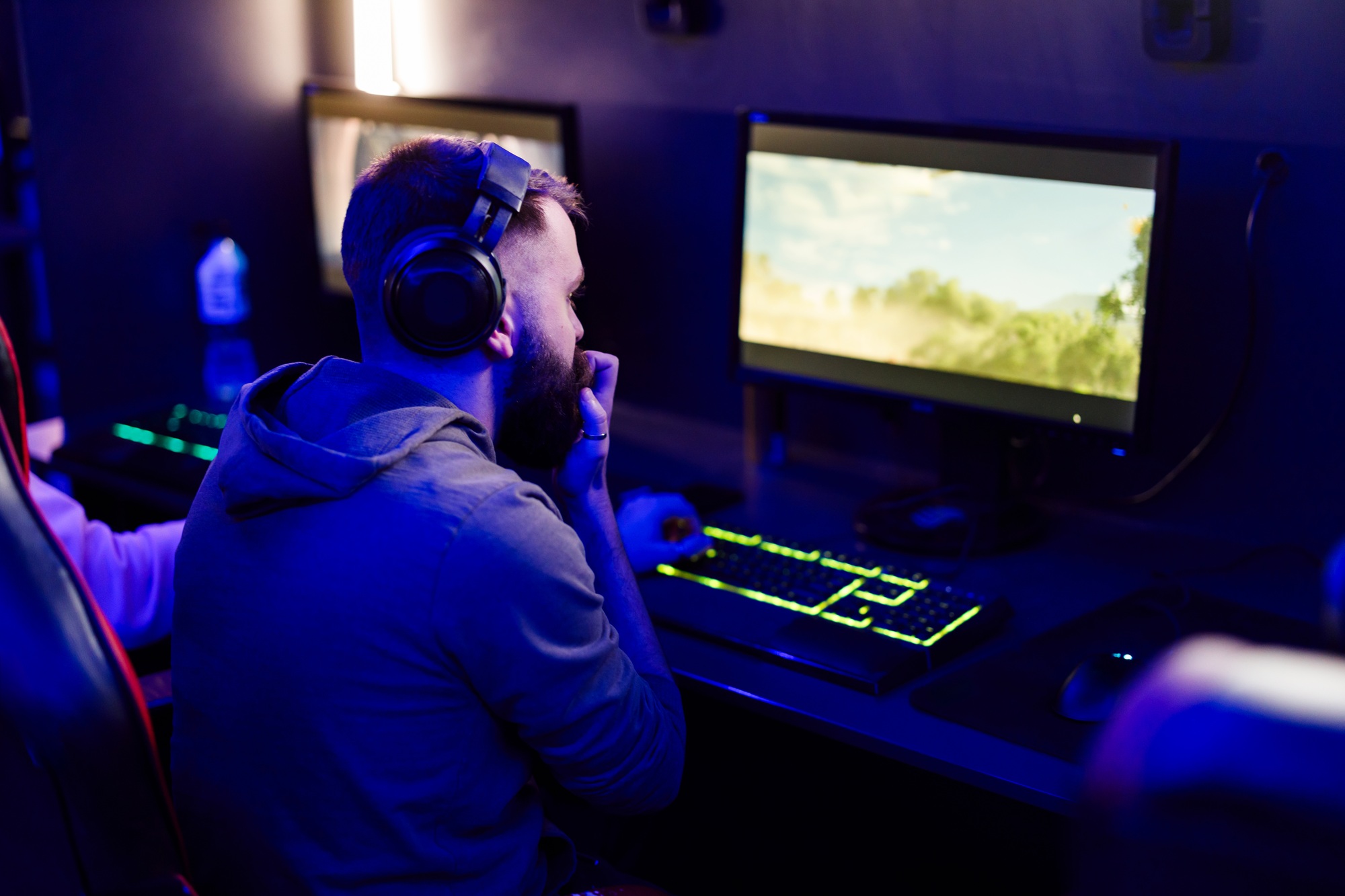 Rear view of uptight gamer playing video game in gaming lounge.